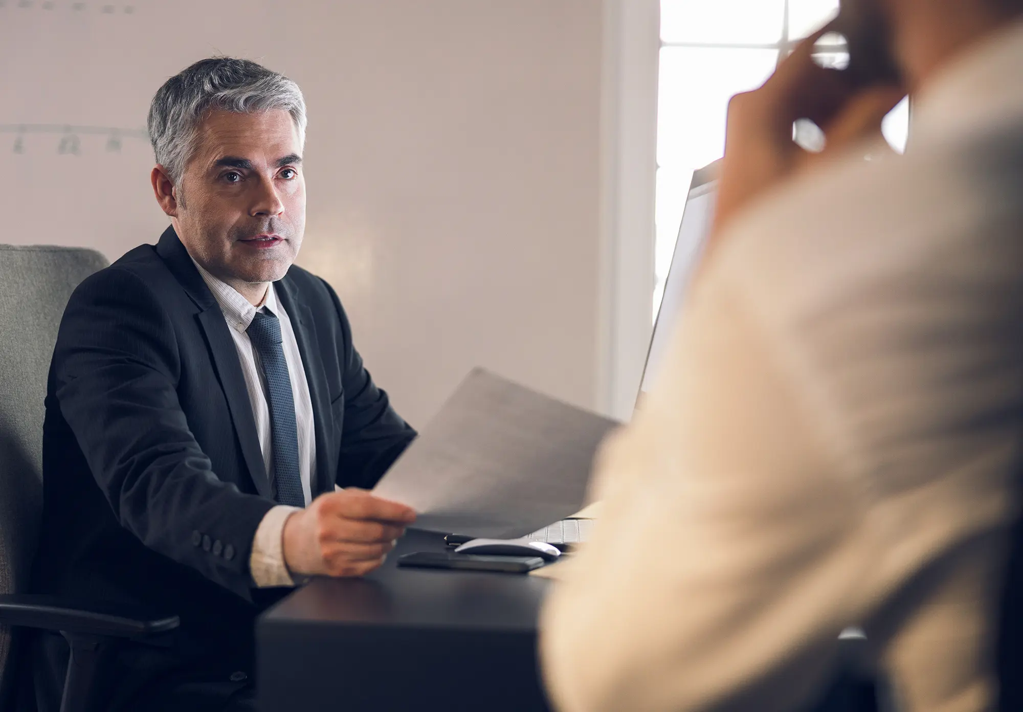 Man handing paperwork to another man