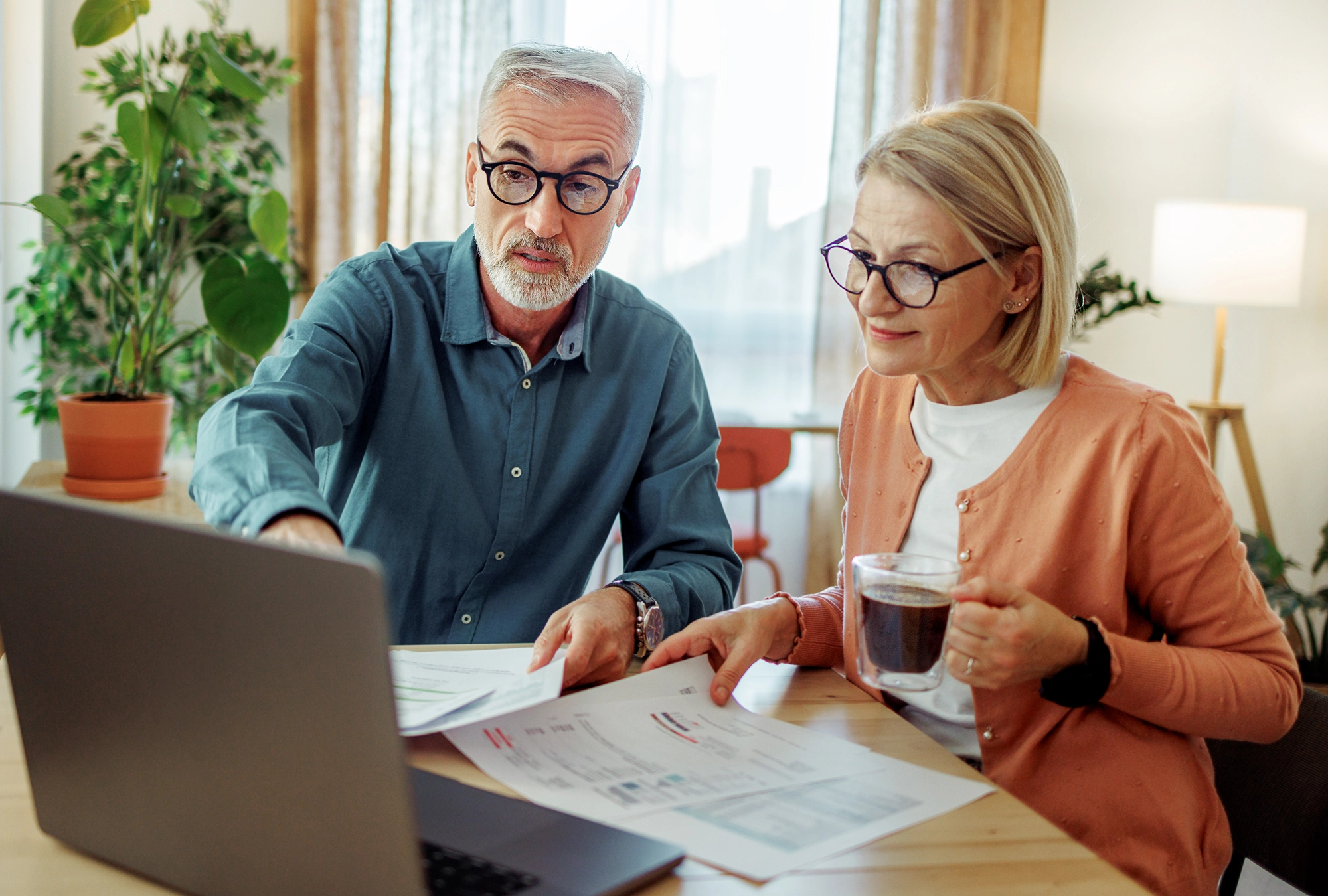 older couple looking at retirement and financial information at the kitchen table