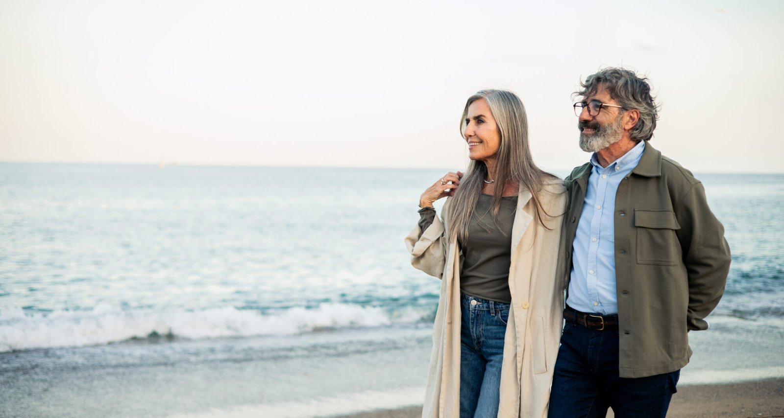 Portrait of a happy mature couple walking on the beach and enjoying their vacation