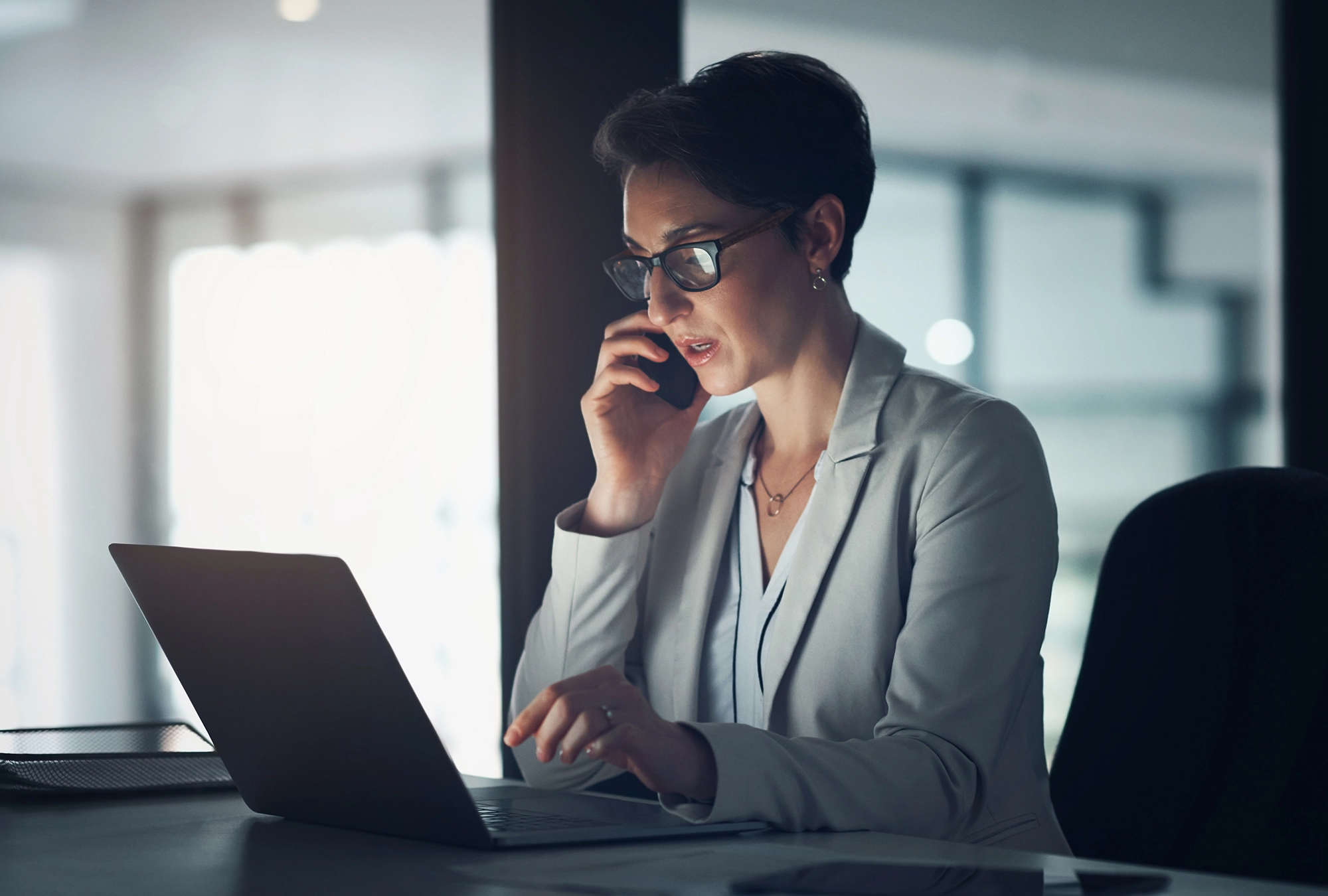 professional in office looking at computer and on the phone